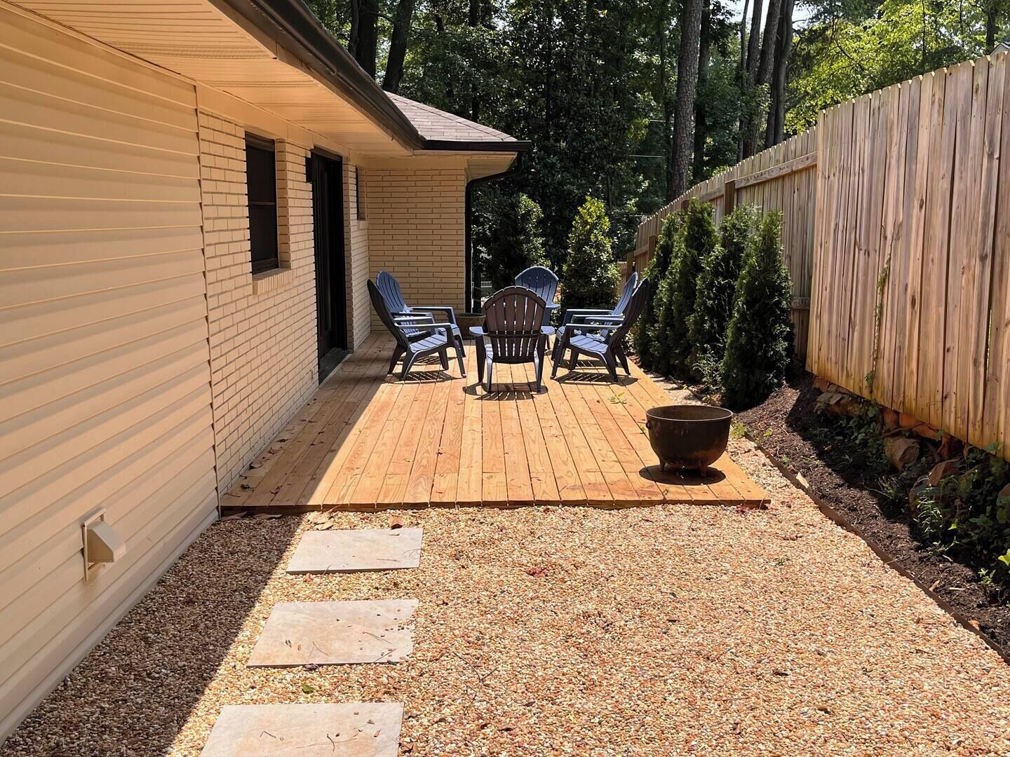 A covered patio with a wooden deck, outdoor furniture, and a fire pit.