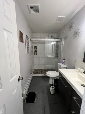 Et badeværelse med bruser, toilet og vask.