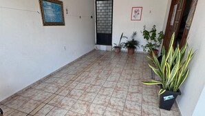 A spacious indoor area with a tiled floor, a ceiling fan, and several potted plants.