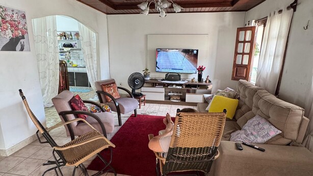 A living room with a wooden ceiling, a TV, a sofa, and two wicker chairs.