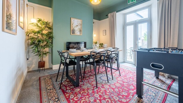 A dining area with a table set for four, a large potted plant, and a foosball table. - Emerald House by Tŷ SA (Newport)