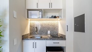 Una cocina moderna con armarios blancos, encimera de granito, microondas, fregadero y lavavajillas.