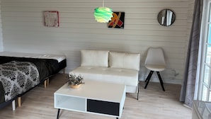 Un dormitorio moderno con cama, sofá y una pequeña mesa con una planta.