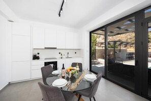 A modern kitchen with white cabinets and a dining area with a glass table and chairs.