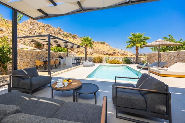 A poolside area with outdoor seating and a stone wall backdrop.