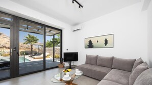 Ein modernes Wohnzimmer mit einem Glastisch, einem grauen Sofa und einem Fernseher.