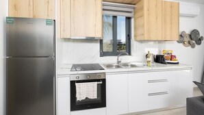 Une cuisine moderne dotée d’appareils électroménagers en acier inoxydable, de meubles en bois, d’une fenêtre et d’un plan de travail sur lequel se trouvent une bouteille et des en-cas.