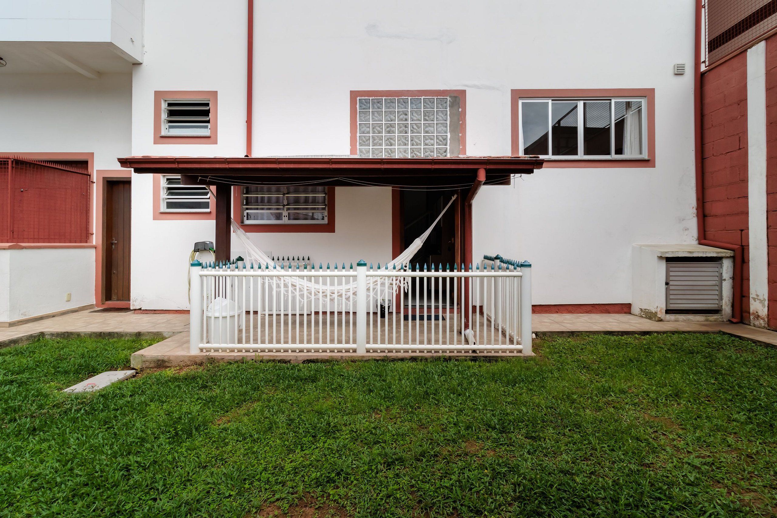 Un edificio blanco con un área de estar cubierta al aire libre y un jardín cercado.