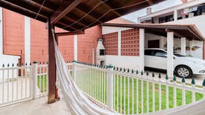 A covered outdoor area with a white fence, a hammock, and a white car parked in the background. - Cozy House in Floripa Rbf142 (Florianópolis)