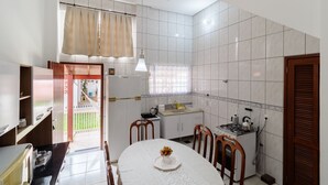 A modern kitchen with white tiles, a dining table with chairs, and a view to the outside. - Cozy House in Floripa Rbf142 (Florianópolis)