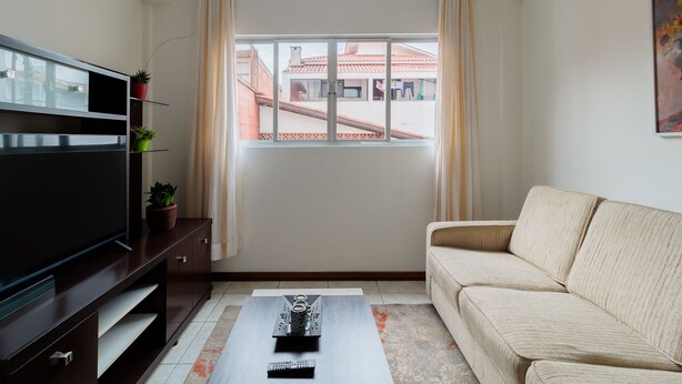 A living room with a TV, sofa, and a window with curtains. - Cozy House in Floripa Rbf142 (Florianópolis)