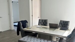 A modern dining area with a rectangular table, four upholstered chairs, and a grey cushioned bench. - Nice, cozy room in Escandon CDMX (Ciudad de México)