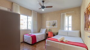 A hotel room with two beds, a ceiling fan, a window with curtains, and a painting on the wall. - Apt 6 min From the sea in Canasvieiras-sc Rba201 (Florianópolis)
