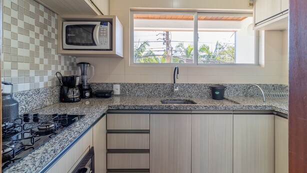 A kitchen with a microwave, stove, sink, and granite countertop. - Apt 6 min From the sea in Canasvieiras-sc Rba201 (Florianópolis)