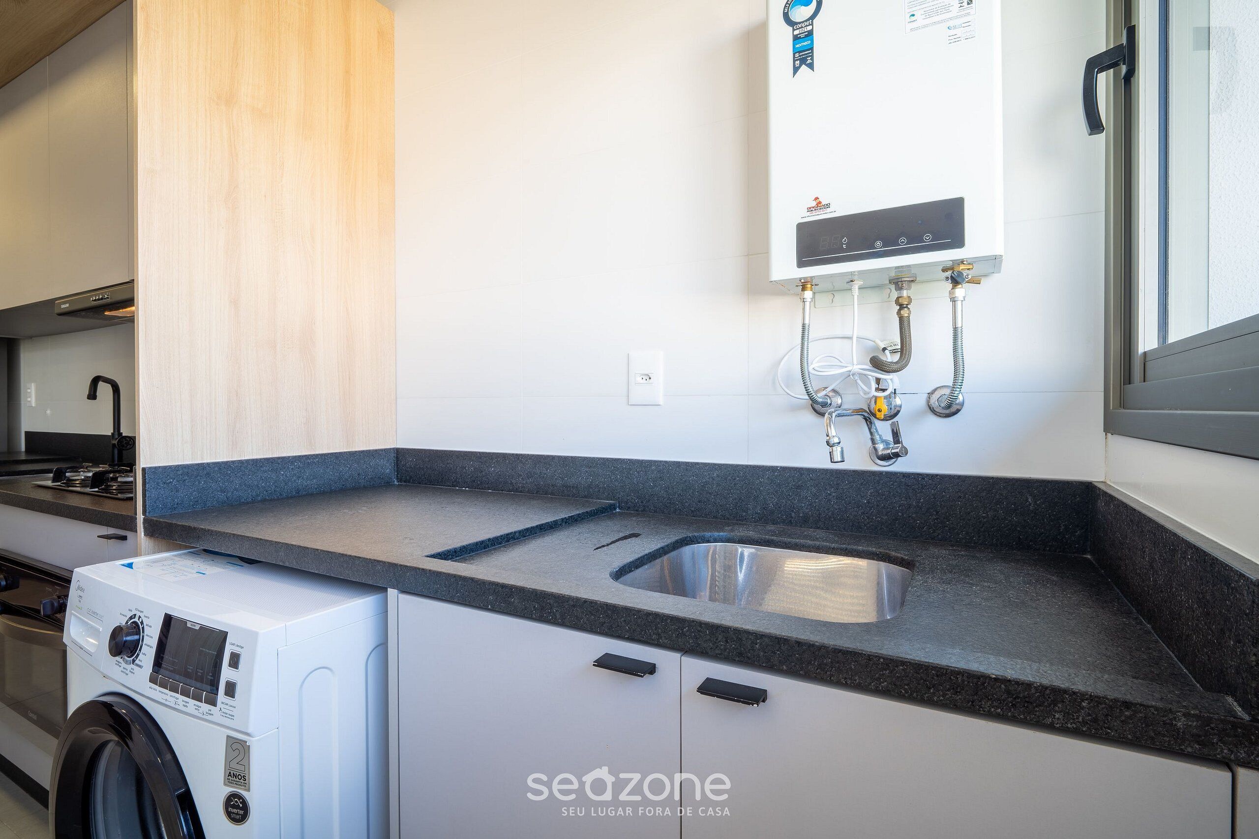 A modern kitchen with a built-in washer, a stainless steel sink, and a wall-mounted water heater.