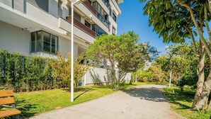 Un edificio moderno con un camino pavimentado, bancos y vegetación.