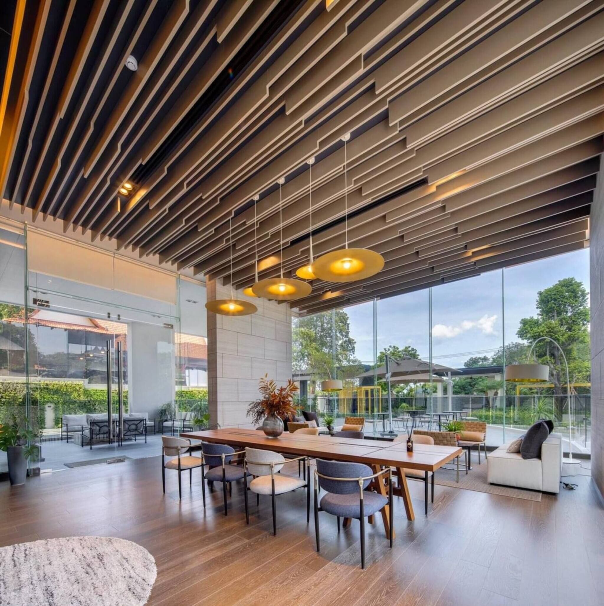 A modern dining area with a long table, multiple chairs, and pendant lighting.