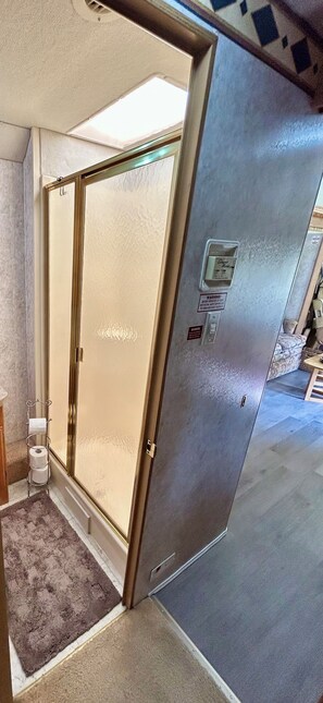Una habitación con puerta corredera que da a un baño, una alfombra pequeña e iluminación de pared.