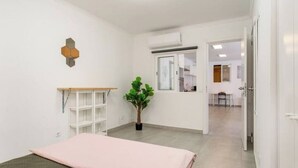 A bedroom with a bed, a small desk, a potted plant, and a window. - Luxury private room with attached bathroom near the beach (Setúbal)