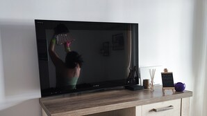 Un téléviseur à écran plat posé sur un meuble télé en bois, avec un tiroir en dessous.