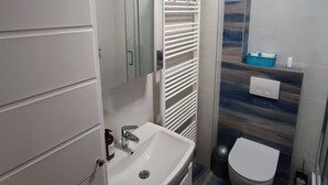 Une salle de bain moderne avec un lavabo blanc, un miroir et un porte-serviettes.