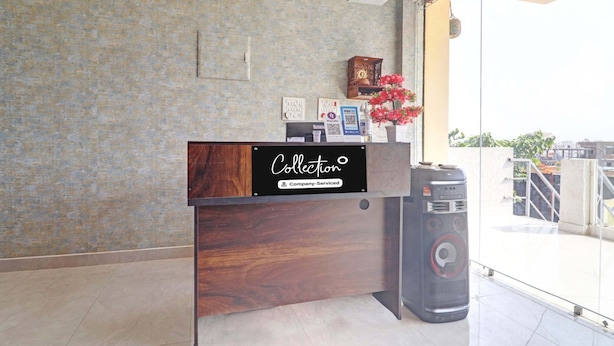 Un mostrador de recepción con detalles de madera, un letrero de la empresa, un reloj y un altavoz.