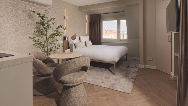 A modern hotel room with a bed, seating area, and a TV. - Zenstay Hotel Amsterdam - Zaandam (Zaandam)