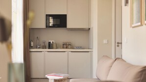 A compact kitchen with a microwave, cabinets, and a small table with a book. - Zenstay Hotel Amsterdam - Zaandam (Zaandam)