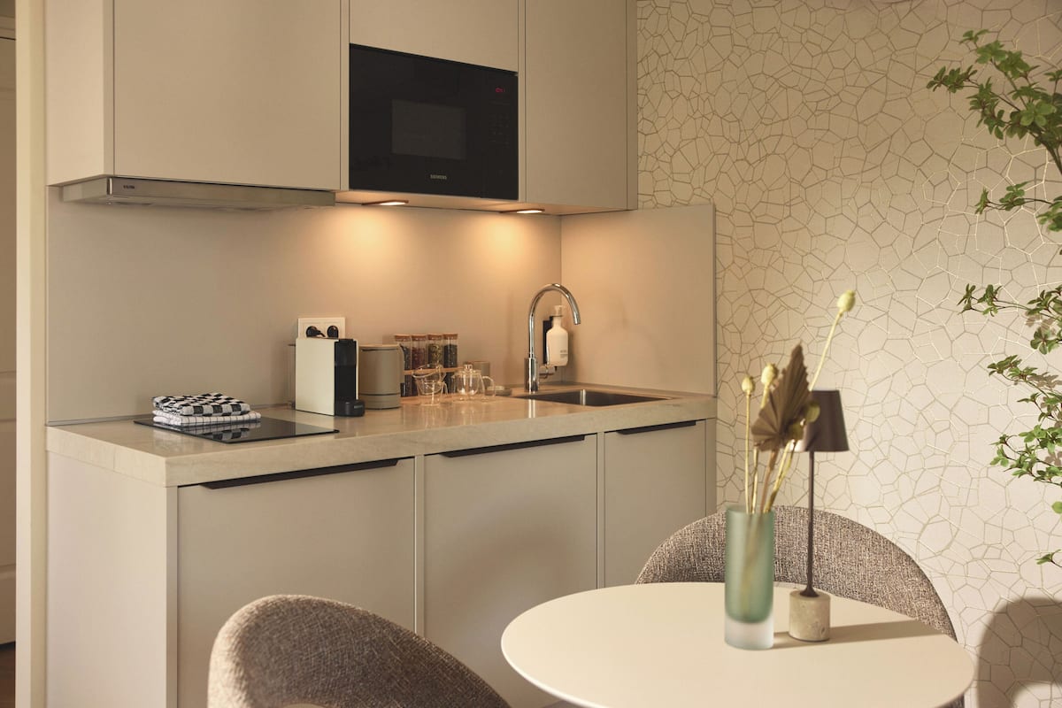 A modern kitchen with a built-in microwave, a sink, and a dining area with a table and chairs.