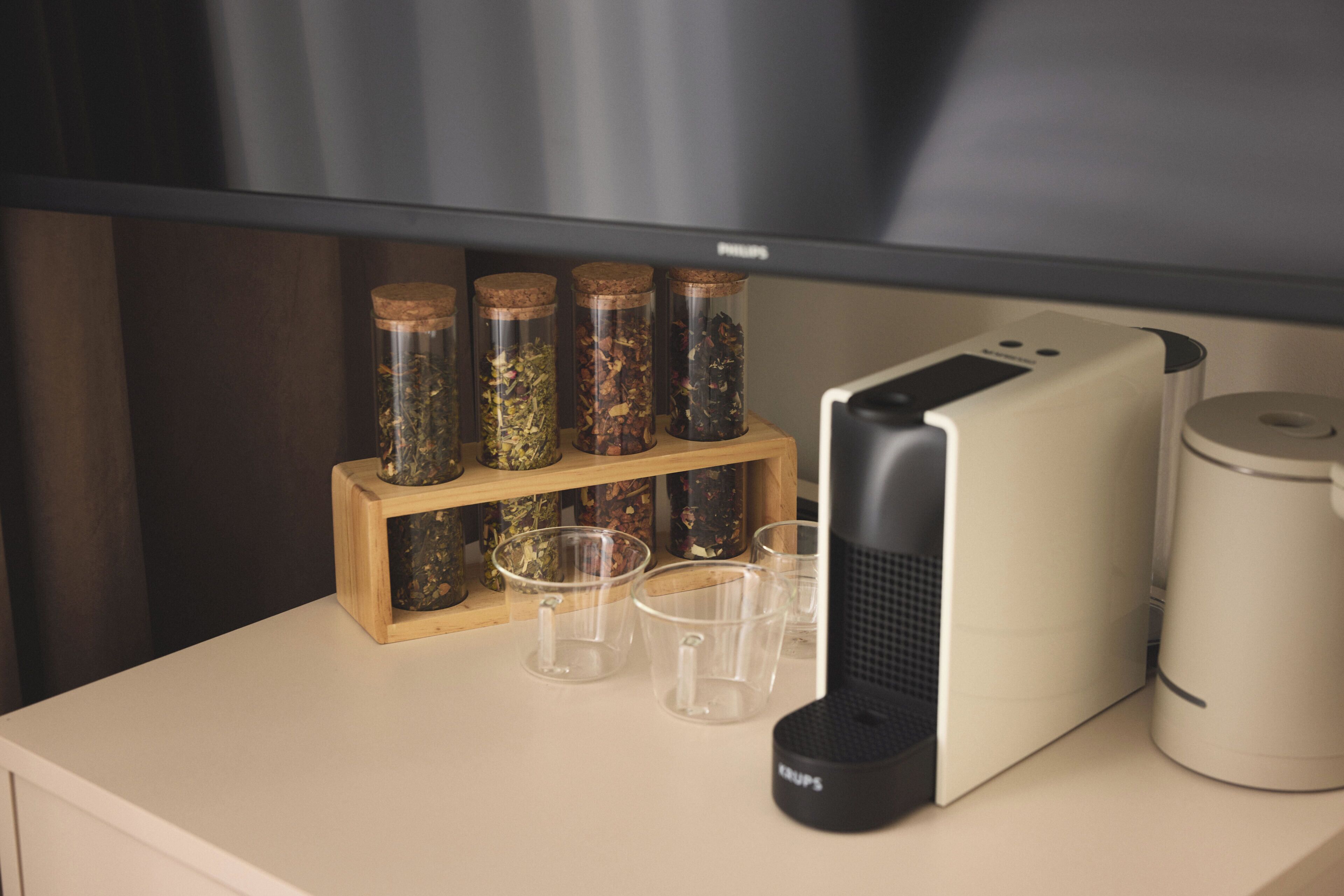 Una encimera de cocina con una cafetera, un tostador y un estante de madera para especias con botes.