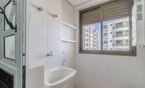 Een badkamer met raam, wastafel en douche.