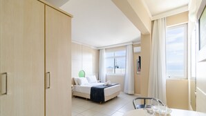A hotel room with a bed, a dining table with glasses, and a view of the sea. - Enjoy Floripa With a sea View! Rah1019 (Florianópolis)