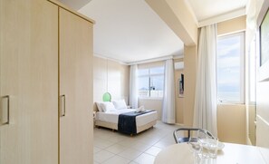 Een hotelkamer met een bed, een eettafel met glazen en uitzicht op zee.
