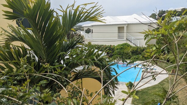 A swimming pool surrounded by lush greenery and a building with a white facade and a balcony. - Sweet Dreams by the Pool - V (Smiths)