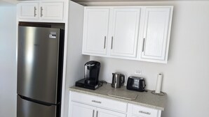 A kitchen with white cabinets, a stainless steel refrigerator, a Keurig coffee maker, a kettle, and a toaster. - Sweet Dreams by the Pool - V (Smiths)