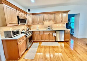 Una cocina moderna con armarios de madera, electrodomésticos de acero inoxidable y un amplio ventanal que aporta luz natural.