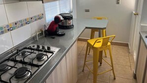 Une cuisine équipée d’une cuisinière à gaz, d’une machine à café et d’une table avec des chaises jaunes.