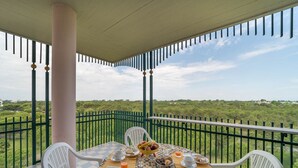 A balcony with a table set for breakfast, chairs, and a view of greenery. - Fabulous Apartment With Premium Amenities (San Michele al Tagliamento)