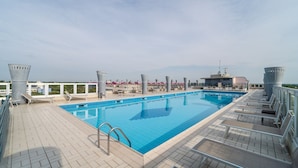 A rooftop swimming pool with lounge chairs and a view of the cityscape. - Fabulous Apartment With Premium Amenities (San Michele al Tagliamento)