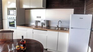 A modern kitchen with white cabinets, a stainless steel refrigerator, a microwave, and a toaster. - Ixora (La Trinité)