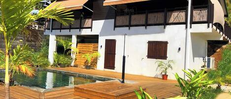 Un bâtiment à deux étages doté d’une piscine et d’une terrasse en bois.