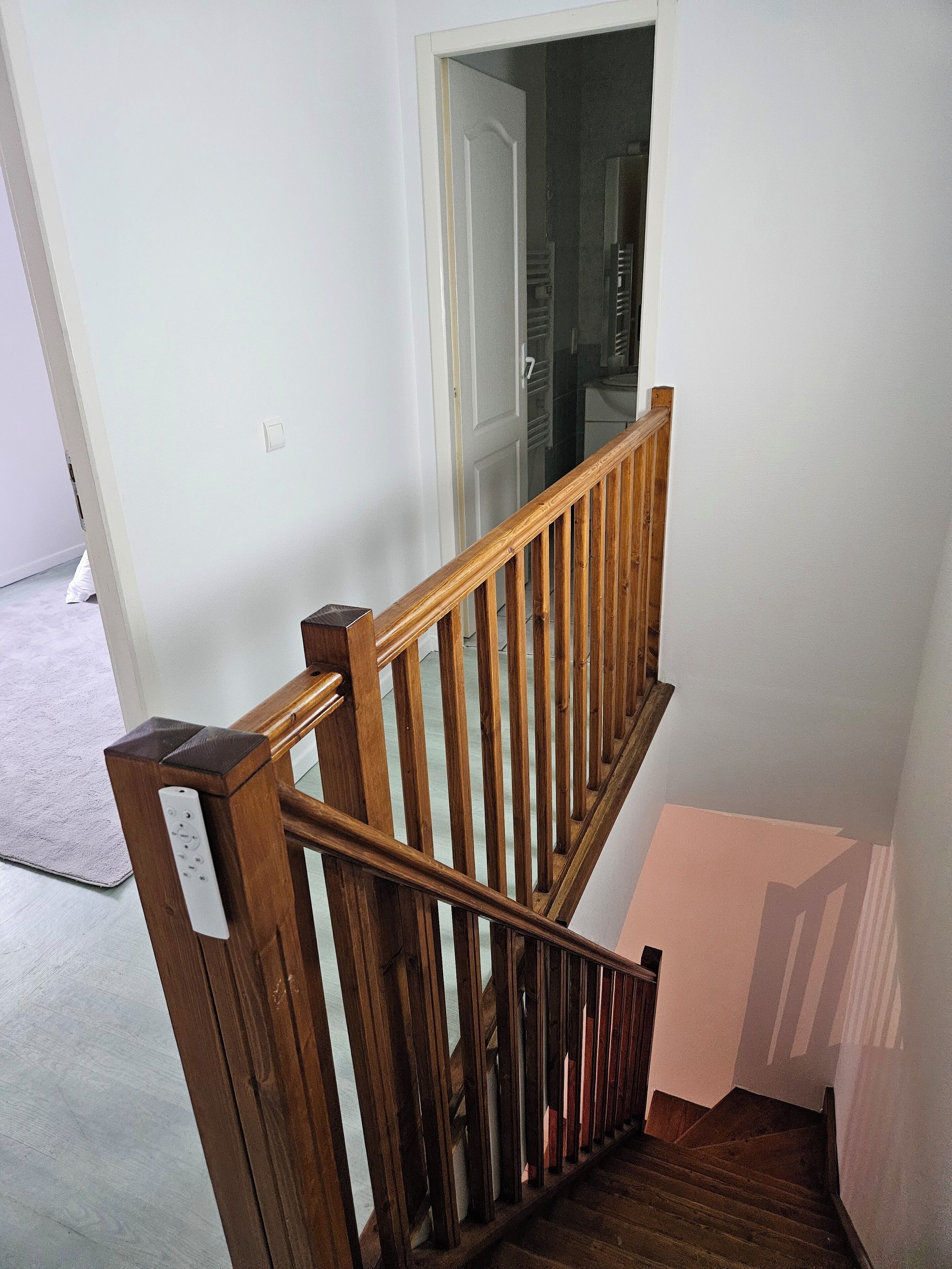 Un escalier en bois, muni d’une rampe, menant à une porte.