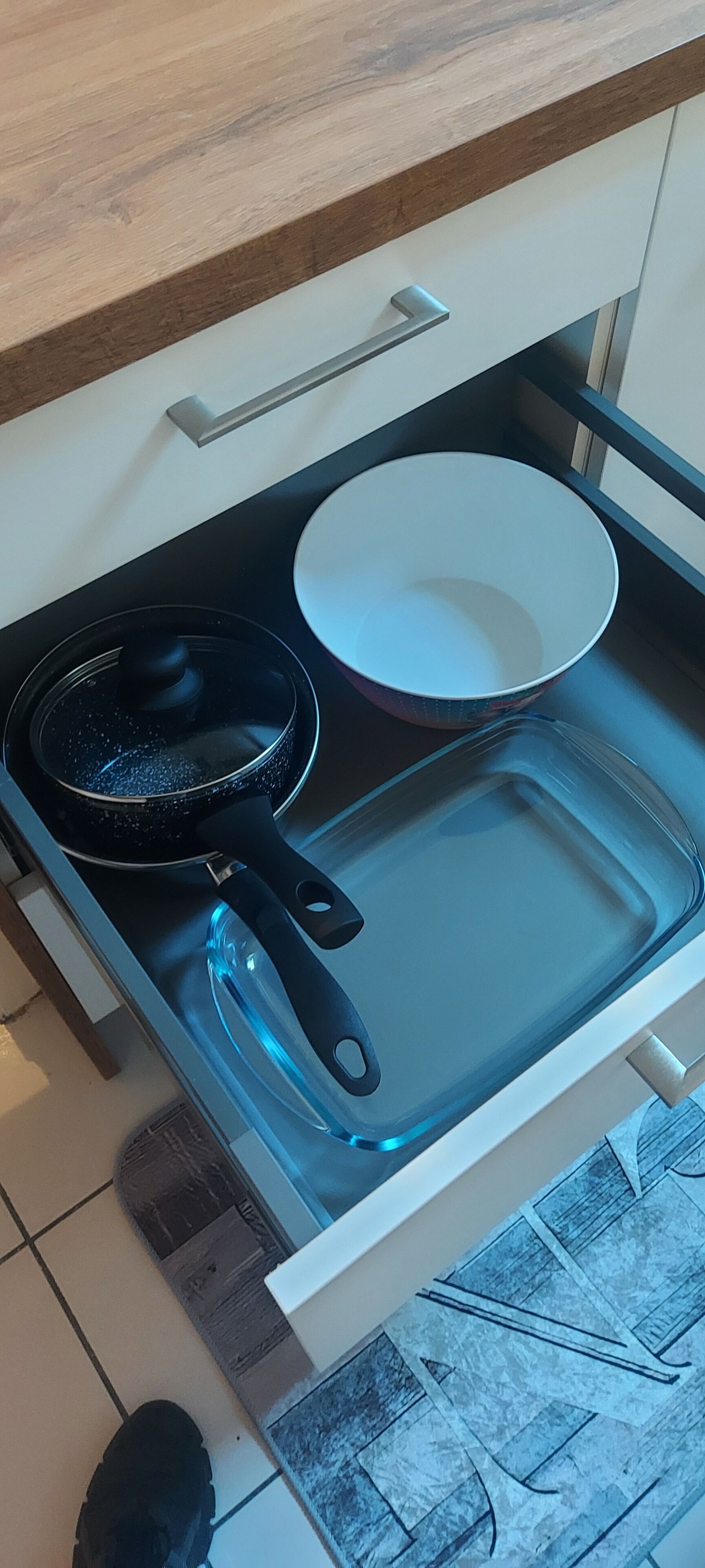 Et køkken med komfur, pande, hvid tallerken og en glas bageform.