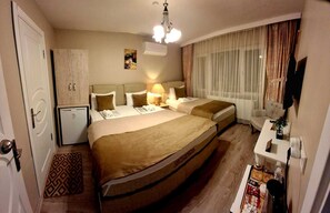 A hotel room with a large bed, bedside tables, a desk, a chair, a small fridge, and a window with curtains. - GÜRSES HOME (Edirne)