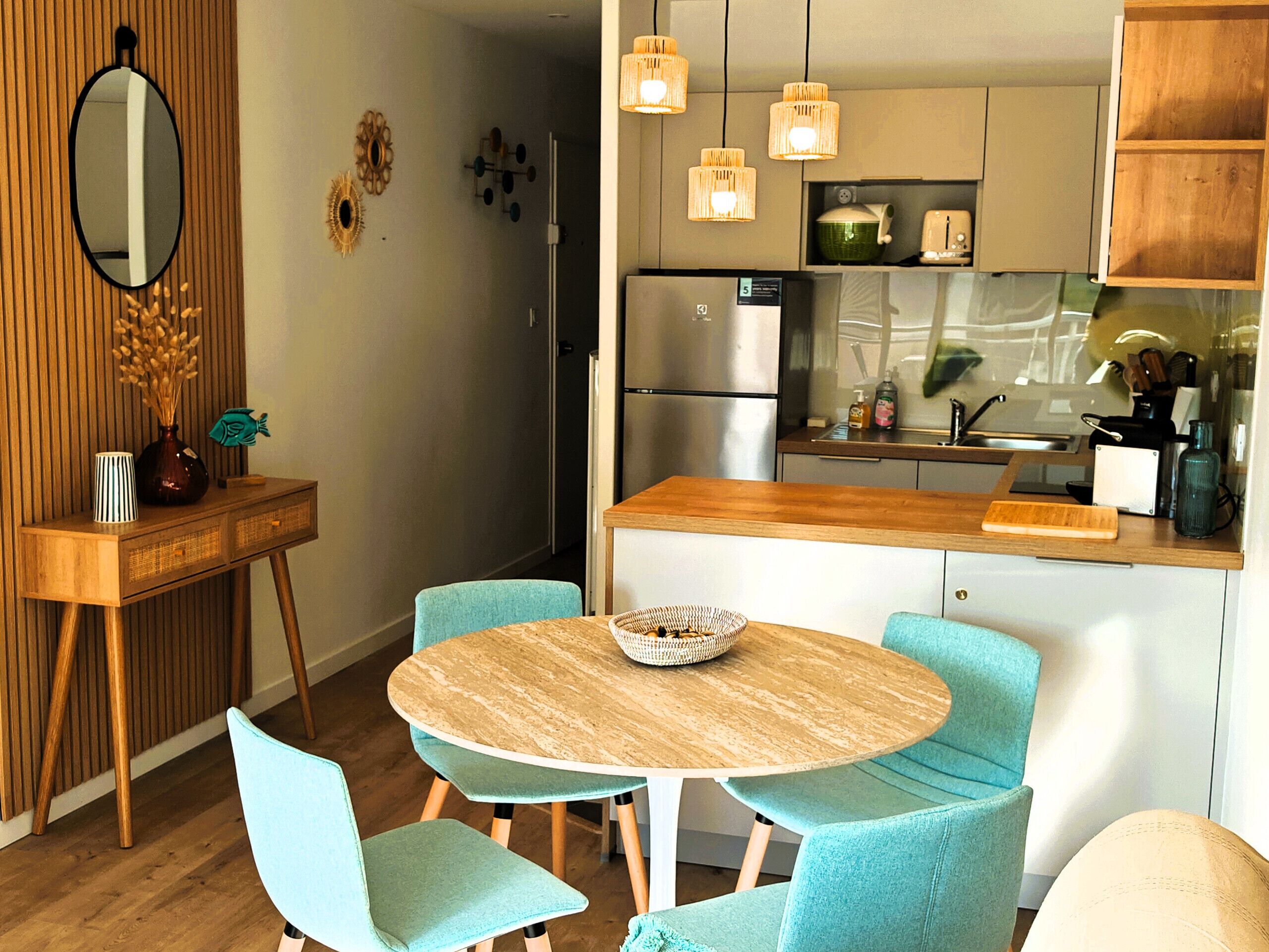 Een moderne keuken met een centraal eiland, lichtblauwe stoelen en een ronde tafel.