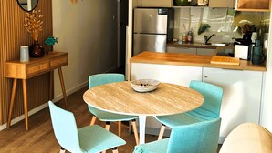 A modern kitchen with a central island, light blue chairs, and a round table. - LA ROSE DES SABLES - Near Beach (Les Sables-d´Olonne)