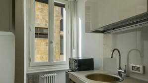 Een kleine keuken met een raam, een ingebouwde toaster, een spoelbak en een radiator.