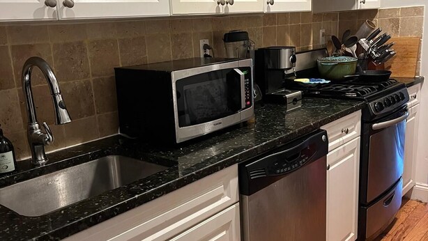 A kitchen with white cabinets, a stainless steel sink, a microwave, a stove, and a dishwasher. - Fully Furnished 1BR Apt Prime E 101st St Location, Steps from Central Park (New York)