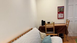A small, cozy room with a wooden bed, a wooden table with a red calendar, and a door. - Fully Furnished 1BR Apt Prime E 101st St Location, Steps from Central Park (New York)