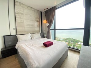Et moderne hotelværelse med en stor seng, et natbord, en lampe og havudsigt.